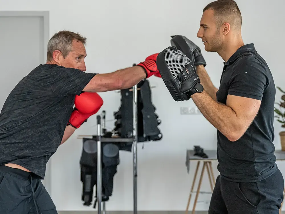 Client aux cheveux gris en séance de boxe avec son coach Get Your Move à Bourgoin-Jallieu