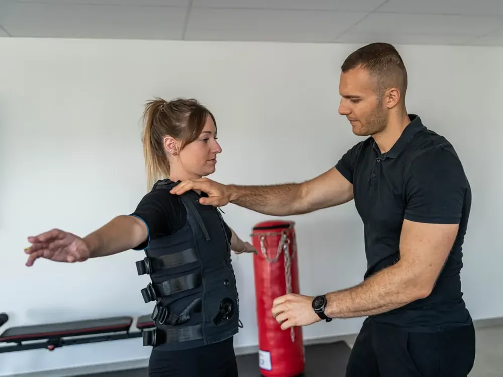 Coach Get Your Move corrigeant la posture d'une cliente en combinaison d'électrostimulation