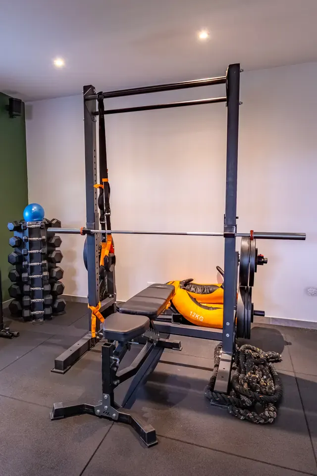 Rack de squat et banc de musculation dans la salle au mur vert de Get Your Move