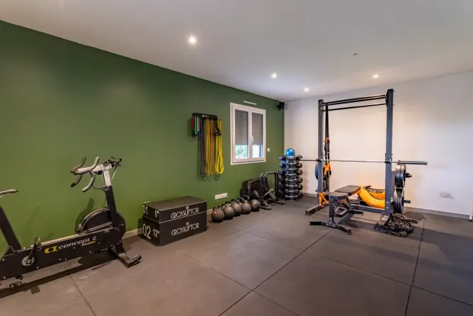 Salle au mur vert avec rack de musculation, vélo et caissons chez Get Your Move