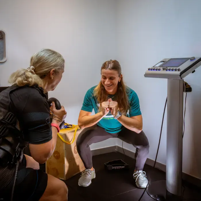 Séance d'électrostimulation chez Get Your Move : cliente en combinaison EMS et coach en squat